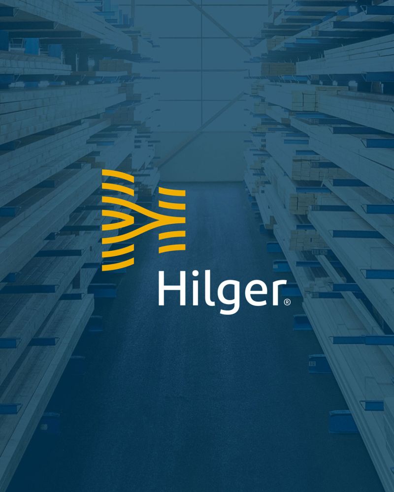 Hilger Holz, Logo vor dunkelblauem Hingtergrund mit Holz im Lager Hilger Holz, Logo vor dunkelblauem Hingtergrund mit Holz im Lager